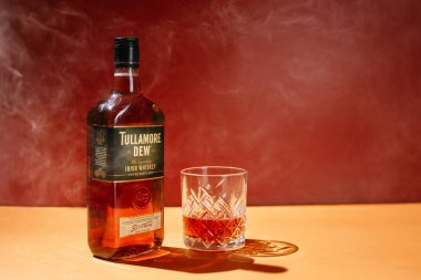 Sarı arka planda bir şişe Tullamore Dew Whiskey.