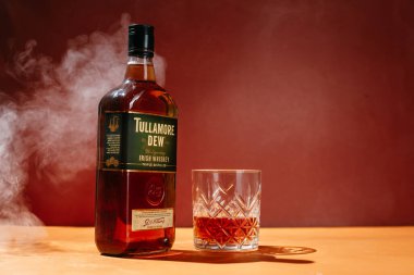 Sarı arka planda bir şişe Tullamore Dew Whiskey.