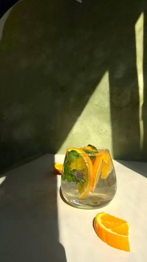 Soğuk limonatayı portakallı ve naneli cam bardakta hazırlama süreci.
