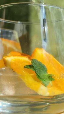 Soğuk limonatayı portakallı ve naneli bir bardakta hazırlama süreci..