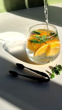 Soğuk limonatayı portakallı ve naneli bir bardakta hazırlama süreci..