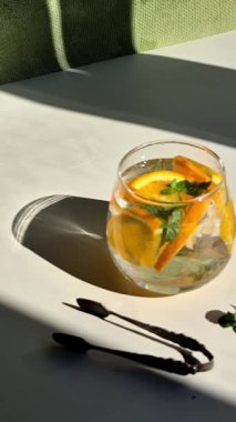 Soğuk limonatayı portakallı ve naneli bir bardakta hazırlama süreci..