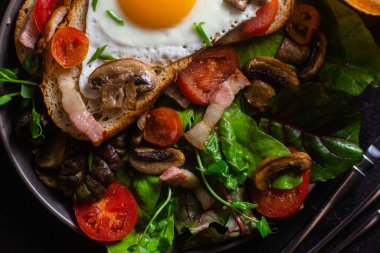 Yağda yumurta, pastırma, domates ve marul tabakta. Kase