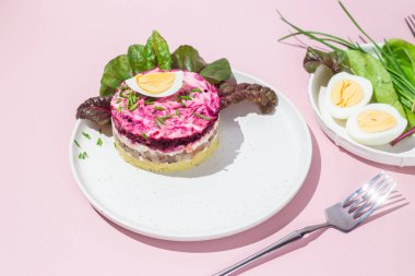 Ringa balıklı salata ve tabakta pancar. Kürk mantonun altında salata.