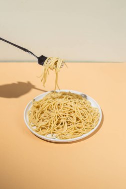 Masadaki beyaz tabakta spagetti yiyen bir kız.