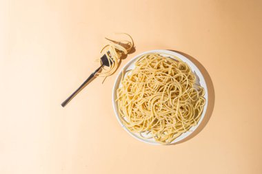 Masadaki beyaz tabakta spagetti yiyen bir kız.