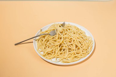 Masadaki beyaz tabakta spagetti yiyen bir kız.