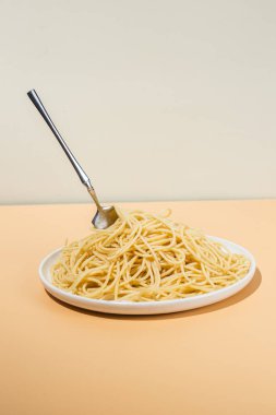 Masadaki beyaz tabakta spagetti yiyen bir kız.