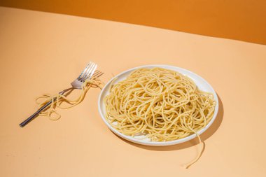 Masadaki beyaz tabakta spagetti yiyen bir kız.