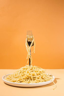 Masadaki beyaz tabakta spagetti yiyen bir kız.