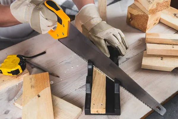Yakından testereyle tahta kiriş kesen bir adam.
