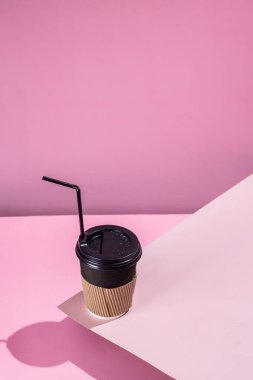 Pembe arka planda bir fincan kağıt kahve.