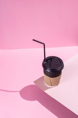 Pembe arka planda bir fincan kağıt kahve.