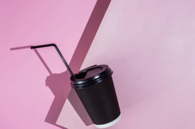 Pembe arka planda bir fincan kağıt kahve.