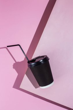 Pembe arka planda bir fincan kağıt kahve.