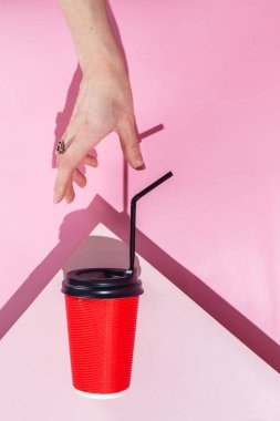 Pembe arka planda bir fincan kağıt kahve.