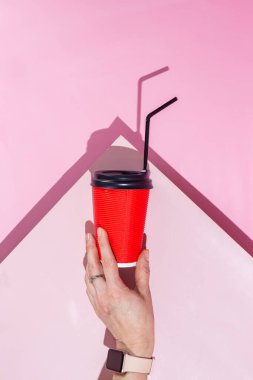 Pembe arka planda bir fincan kağıt kahve.