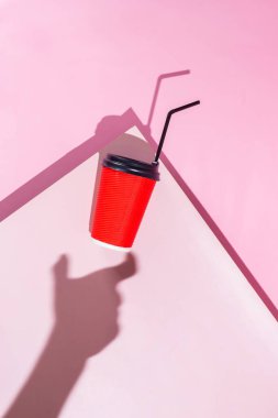 Pembe arka planda bir fincan kağıt kahve.