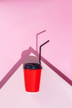 Pembe arka planda bir fincan kağıt kahve.