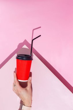 Pembe arka planda bir fincan kağıt kahve.