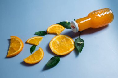 Mavi arka planda portakal suyu ve portakal dilimleri.