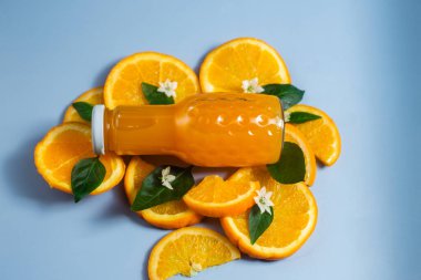 Mavi arka planda portakal suyu ve portakal dilimleri.