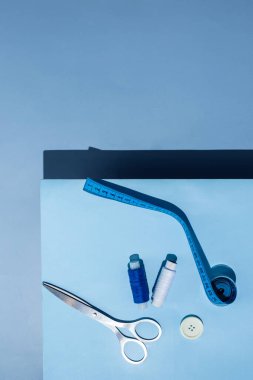 Aksesuar dikiyorum. İplikler, makas, mezura, mavi arkaplandaki düğmeler