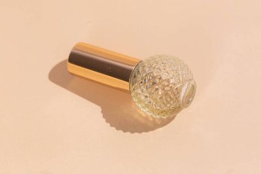 Bej arka planda zarif bir altın parfüm şişesi..