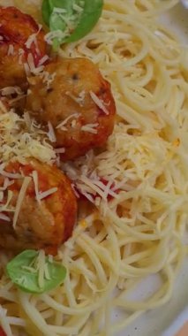Köfteli spagetti, domates soslu, beyaz tabakta peynirli, bej arka planda.