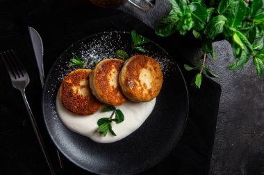 Krem soslu peynirli kekler ve masada siyah bir tabakta nane şekeri. Kahvaltı.