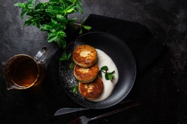 Krem soslu peynirli kekler ve masada siyah bir tabakta nane şekeri. Kahvaltı.