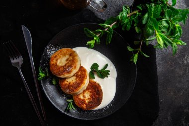 Krem soslu peynirli kekler ve masada siyah bir tabakta nane şekeri. Kahvaltı.