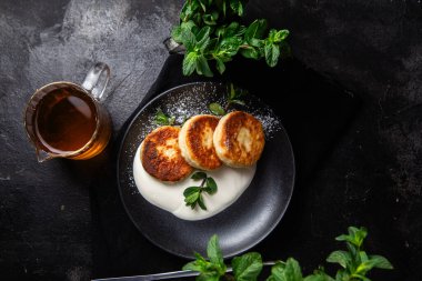 Krem soslu peynirli kekler ve masada siyah bir tabakta nane şekeri. Kahvaltı.