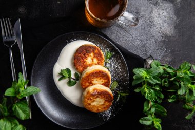 Krem soslu peynirli kekler ve masada siyah bir tabakta nane şekeri. Kahvaltı.