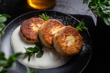 Krem soslu peynirli kekler ve masada siyah bir tabakta nane şekeri. Kahvaltı.