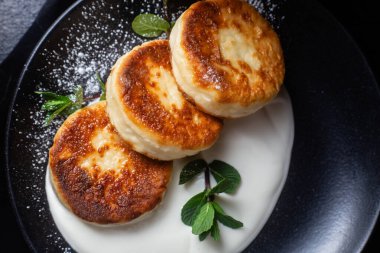 Krem soslu peynirli kekler ve masada siyah bir tabakta nane şekeri. Kahvaltı.