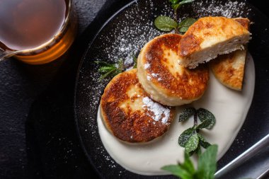 Krem soslu peynirli kekler ve masada siyah bir tabakta nane şekeri. Kahvaltı.
