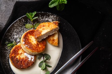 Krem soslu peynirli kekler ve masada siyah bir tabakta nane şekeri. Kahvaltı.