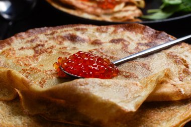 Masanın üzerinde siyah bir tabakta kırmızı havyarlı gözleme. Kahvaltı Maslenitsa