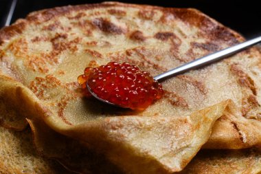 Masanın üzerinde siyah bir tabakta kırmızı havyarlı gözleme. Kahvaltı Maslenitsa