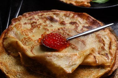 Masanın üzerinde siyah bir tabakta kırmızı havyarlı gözleme. Kahvaltı Maslenitsa