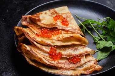 Masanın üzerinde siyah bir tabakta kırmızı havyarlı gözleme. Kahvaltı Maslenitsa