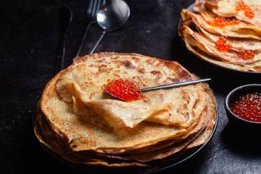 Masanın üzerinde siyah bir tabakta kırmızı havyarlı gözleme. Kahvaltı Maslenitsa