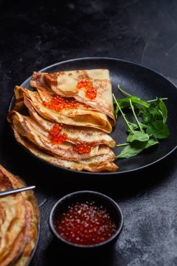 Masanın üzerinde siyah bir tabakta kırmızı havyarlı gözleme. Kahvaltı Maslenitsa