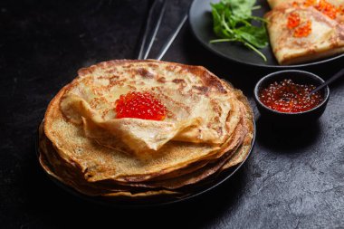 Masanın üzerinde siyah bir tabakta kırmızı havyarlı gözleme. Kahvaltı Maslenitsa