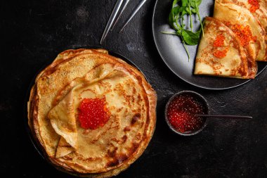 Masanın üzerinde siyah bir tabakta kırmızı havyarlı gözleme. Kahvaltı Maslenitsa