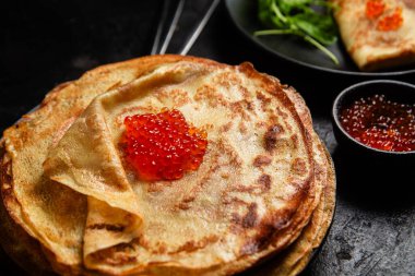 Masanın üzerinde siyah bir tabakta kırmızı havyarlı gözleme. Kahvaltı Maslenitsa