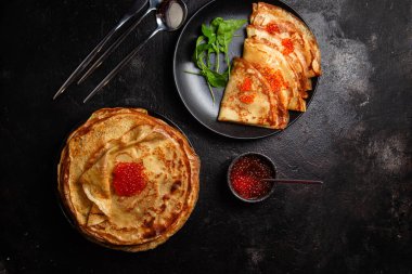 Masanın üzerinde siyah bir tabakta kırmızı havyarlı gözleme. Kahvaltı Maslenitsa