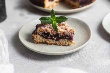 Siyah üzümlü yuvarlak turta ve masada bir tabakta nane şekeri. Tatlı.