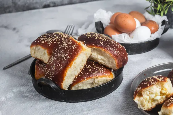 Masadaki tabakta yumurta ve susam tohumlu fırında turtalar. Maya turtaları.
